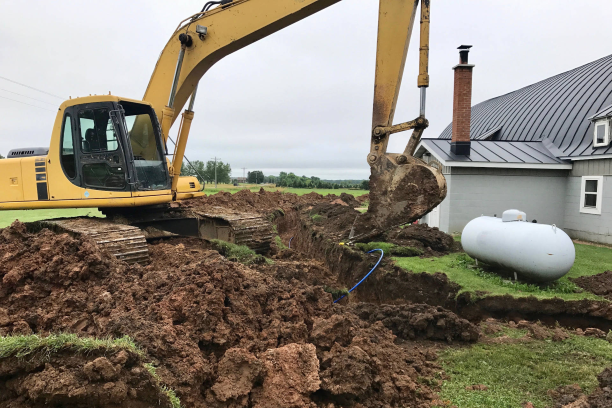 Excavator digging trenches for septic tank system replacement